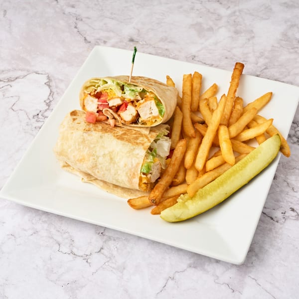 Two chicken wraps with lettuce and tomato, served with golden fries and a pickle spear on a white plate.