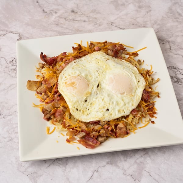 Watertown Cafe's breakfast skillet with two fried eggs, bacon, ham, hash browns, and shredded cheese.